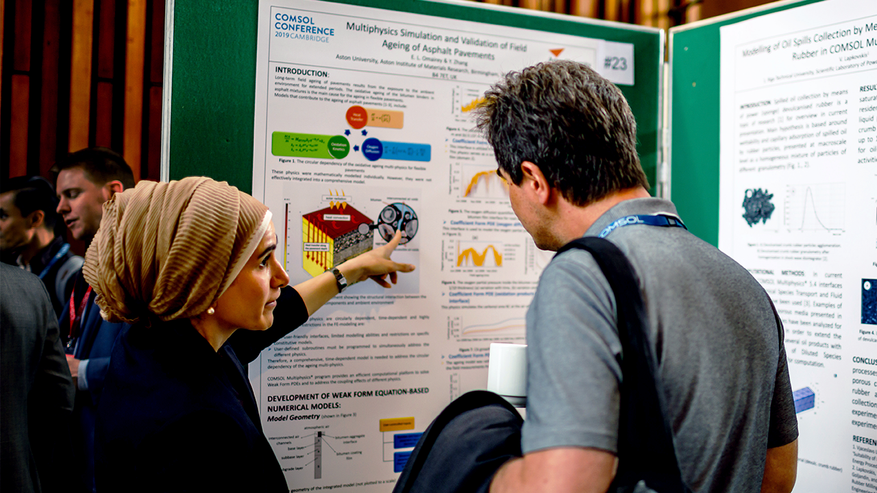 Two people viewing a COMSOL Conference poster on the simulation of field aging of asphalt pavements.